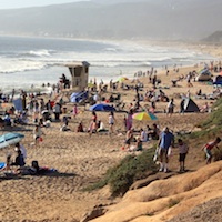 Crowds of people enjoying the sun and beach in Half Moon Bay